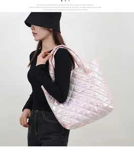 Modell trägt eine große rosa schimmernde gesteppte Tragetasche mit schwarzem Outfit