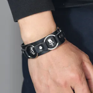 Dettaglio di un bracciale punk in pelle nera con teschi argentati e borchie.