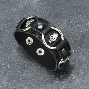 Dettaglio macro del bracciale in pelle punk con teschi in metallo e borchie argento