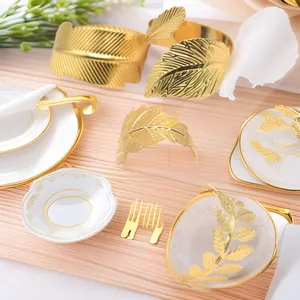 Detailed view of elegant golden leaf metal napkin rings on a white porcelain dinner plate.