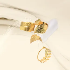 Detailed view of four elegant gold metal leaf napkin rings on a soft cream background.