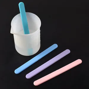 Detail view of four reusable colorful silicone stirring sticks and a 250ml measuring cup