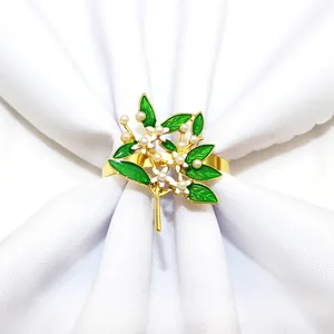 Rond de serviette en émail fleur de gardénia avec feuilles vertes et perles dorées.