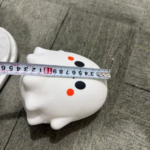 Measurement of white ghost squishy toy showing its width with a tape measure