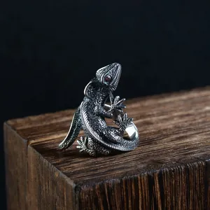 Detailed view of a vintage silver lizard ring with red eye on wood texture