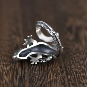 Detail shot of vintage silver lizard ring with intricate scale textures on dark wood background
