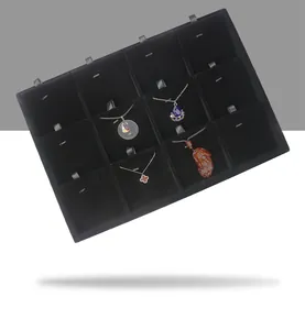 Detail view of black velvet jewelry tray with multiple slots for necklace display.