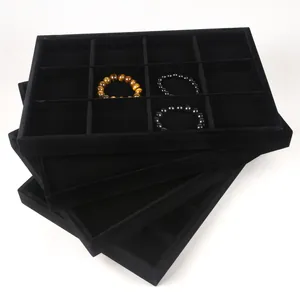 Stack of black velvet jewelry trays for organizing bracelets and necklaces