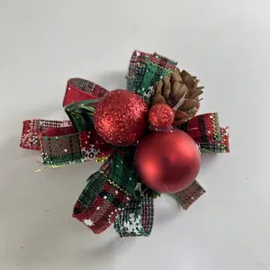 Close-up of festive Christmas decoration featuring red plaid bow, pinecone and red ornaments