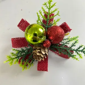 Close-up of Christmas decoration with red burlap bow, pinecone, and festive baubles.