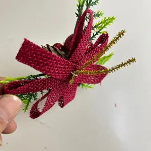 Close-up detail of a Christmas decorative pick with a red burlap bow and pine needles.