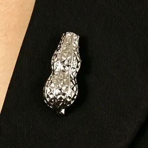 Vista dettagliata di una spilla a forma di arachide argento con superficie metallica strutturata
