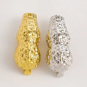 Dettaglio di spillette metalliche a forma di arachide in elegante finitura oro e argento