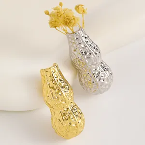 Dettaglio della spilla a forma di nocciolina con inserto floreale in oro e argento