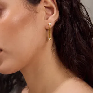 Vue détaillée de boucles d'oreilles à pampilles en acier doré 18K avec des pierres de zircon.