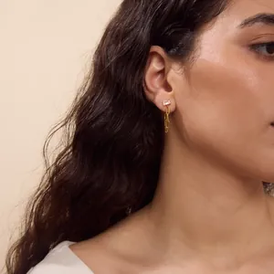 Vue détaillée de boucles d'oreilles dorées en zircone avec chaîne amovible.