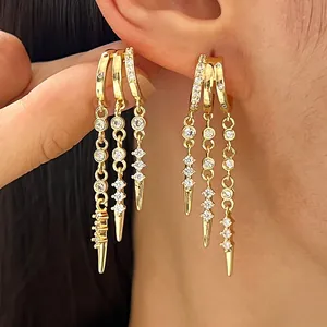 Detailed view of stylish gold hoop earrings featuring sparkling cubic zirconia and rivet tassels.