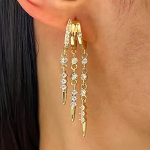 Macro detail of trendy gold hoop earrings with zircon tassels and punk spikes on ear