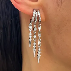 Detailed close-up of zircon-inlaid silver tassel hoop earrings with spike pendants.