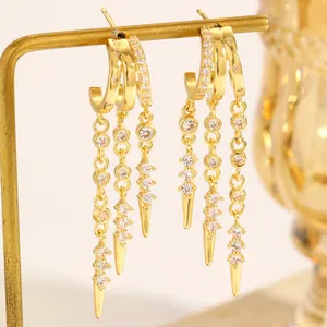 Detailed macro view of gold tassel hoop earrings featuring sparkling zirconia and rivet drops.