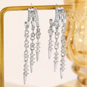 Close-up of silver-tone hoop earrings with zircon tassels and rivet pendant details.