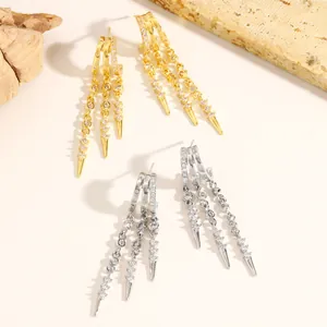 Close-up of gold and silver fringe hoop earrings with zircons and spike tassels.