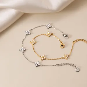 Detail view of 18K gold plated stainless steel bracelets with sparkly flower zircon charms.