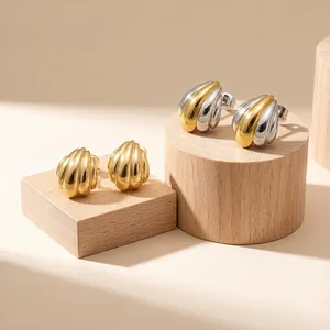 Vista dettagliata di orecchini bicolore a forma di conchiglia su supporti in legno.
