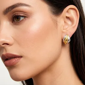 Primo piano di eleganti orecchini bicolore a forma di ventaglio sull'orecchio della modella
