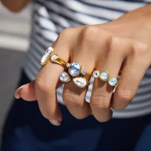 Nahaufnahme von Edelstahl-Offenringen mit blauen und weißen Kristallen an einer Hand.