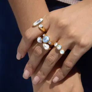 Detailansicht mehrerer vergoldeter Edelstahlringe mit bunten Kristallsteinen am Finger