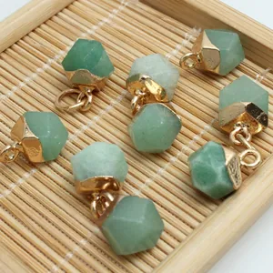 Macro detail of green faceted gemstone pendants with gold caps on a natural bamboo mat