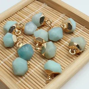 Close-up of multifaceted light blue stone pendants with gold loops for DIY jewelry