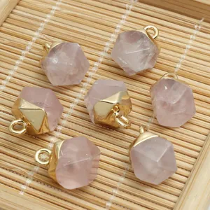 Close-up of hexagonal faceted rose quartz charms with golden metal caps for DIY jewelry