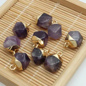 Close-up of faceted purple amethyst crystal pendants with gold-plated caps for DIY crafts