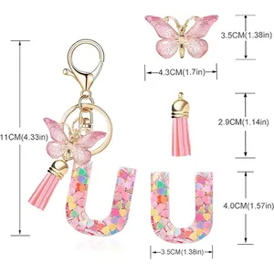 Detailed view of 'U' letter keychain with butterfly, pink tassel, and heart sequins