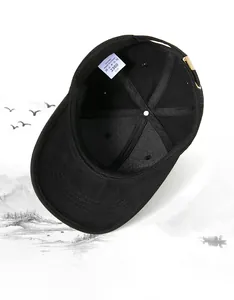 Detail view of internal cotton tag and adjustable metal buckle of a black baseball cap