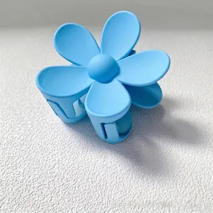 Gros plan détaillé d'une pince à cheveux mate bleu clair en forme de fleur élégante.