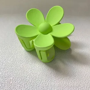 Gros plan d'une pince à cheveux fleur vert lime mat avec des pétales vibrants