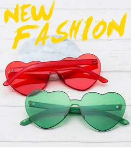 Close-up of red and green heart-shaped rimless jelly sunglasses on white wood
