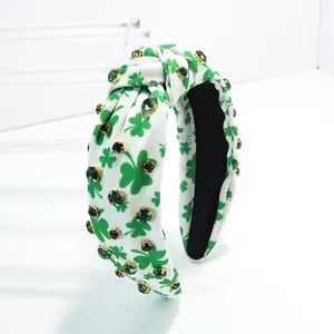 Close-up of green clover print knotted headband with emerald rhinestones.