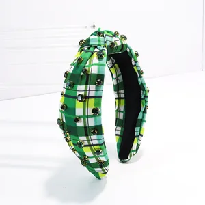Close-up of a green plaid knotted headband with sparkling green rhinestone accents