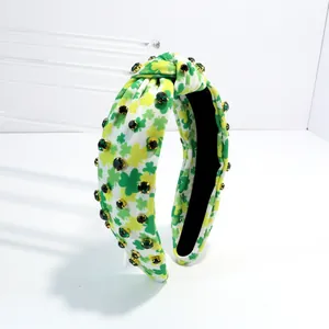 Close-up detail of a vintage wide-brim knotted headband with green shamrock print.