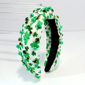 Detail view of the green shamrock pattern and rhinestone studs on the knotted headband