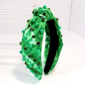 Close-up of a green shamrock knotted headband with emerald rhinestones and pearls.