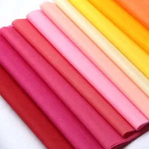 Macro shot of layered colorful tissue paper assortment in red, pink, and yellow tones.
