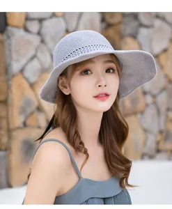 Elegante modelo asiática luciendo un sombrero de sol de punto gris de ala ancha para el verano
