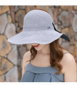 Primer plano detallado de un sombrero de sol tejido púrpura con un elegante lazo negro.