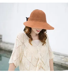Mujer elegante con sombrero de sol de punto marrón de ala ancha y un lazo negro decorativo