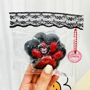 Detailed close-up of a soft black and red glitter cat paw squishy toy in lace packaging